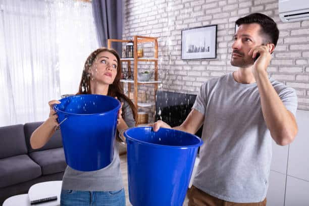 Couple Using Bucket For Collecting Water Leakage From Ceiling And Calling Plumber On Cellphone SAINT CLOUD FLORIDA RESTOWATERDAMAGE